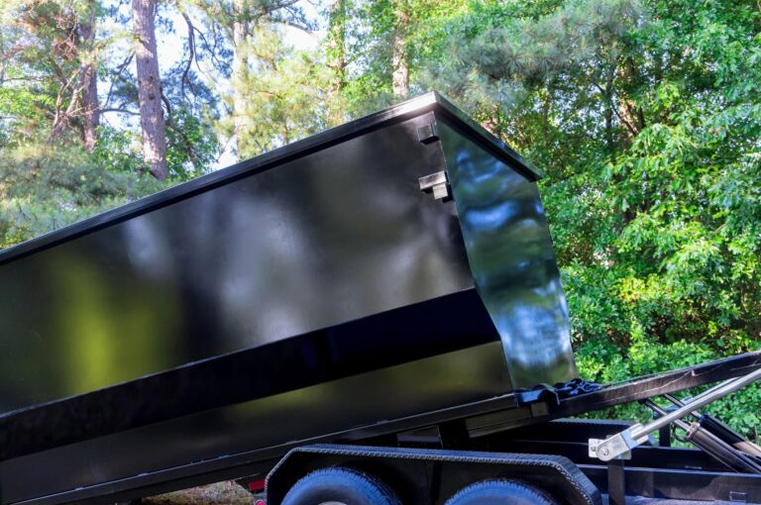 Black dump trailer in forested area