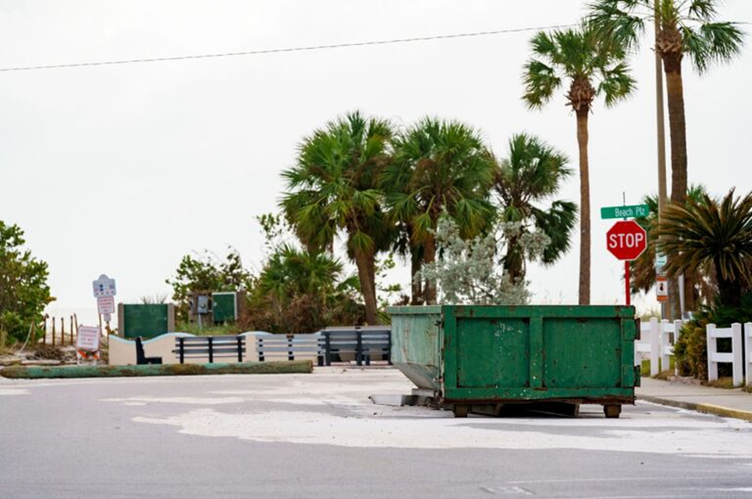 Street with green dumpster and palm trees