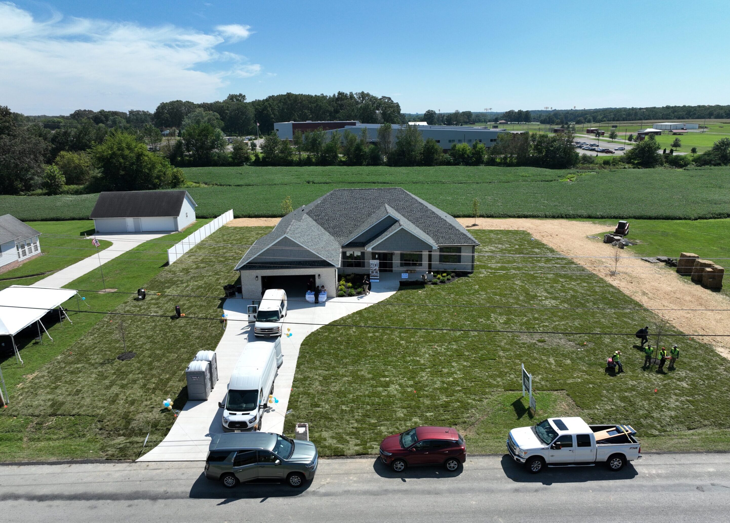 A modern house with vehicles parked in front on a sunny day.