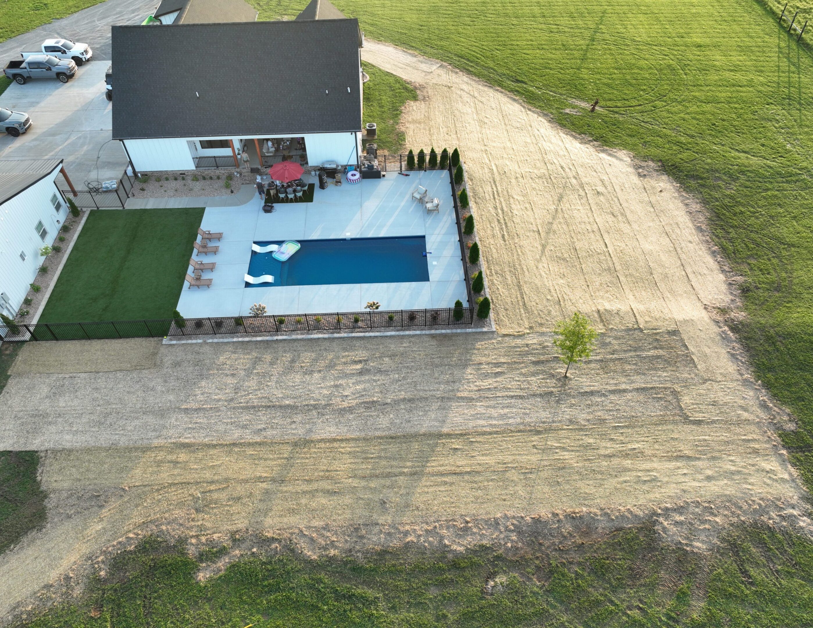 A backyard with a swimming pool and patio furniture beside a house.